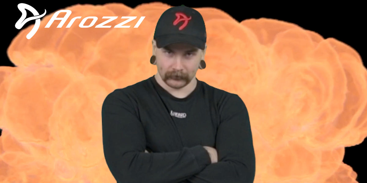 Man in black shirt and cap stands arms crossed, orange explosion and Arozzi logo behind him.