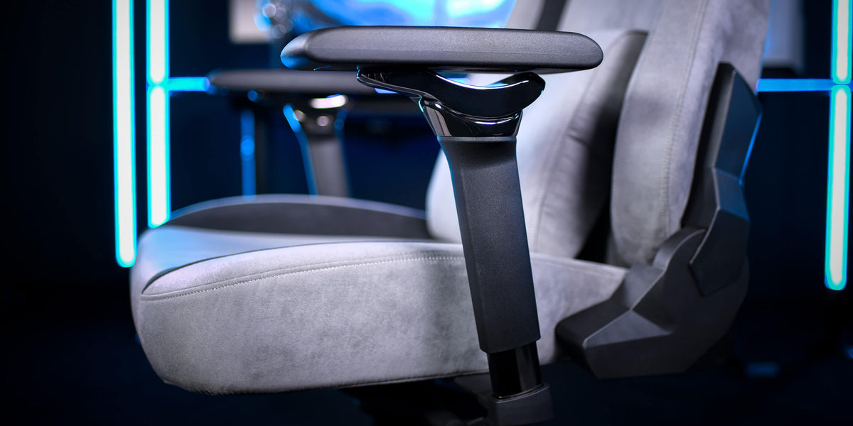 Close-up of a gray gaming chair armrest with blurred blue background.
